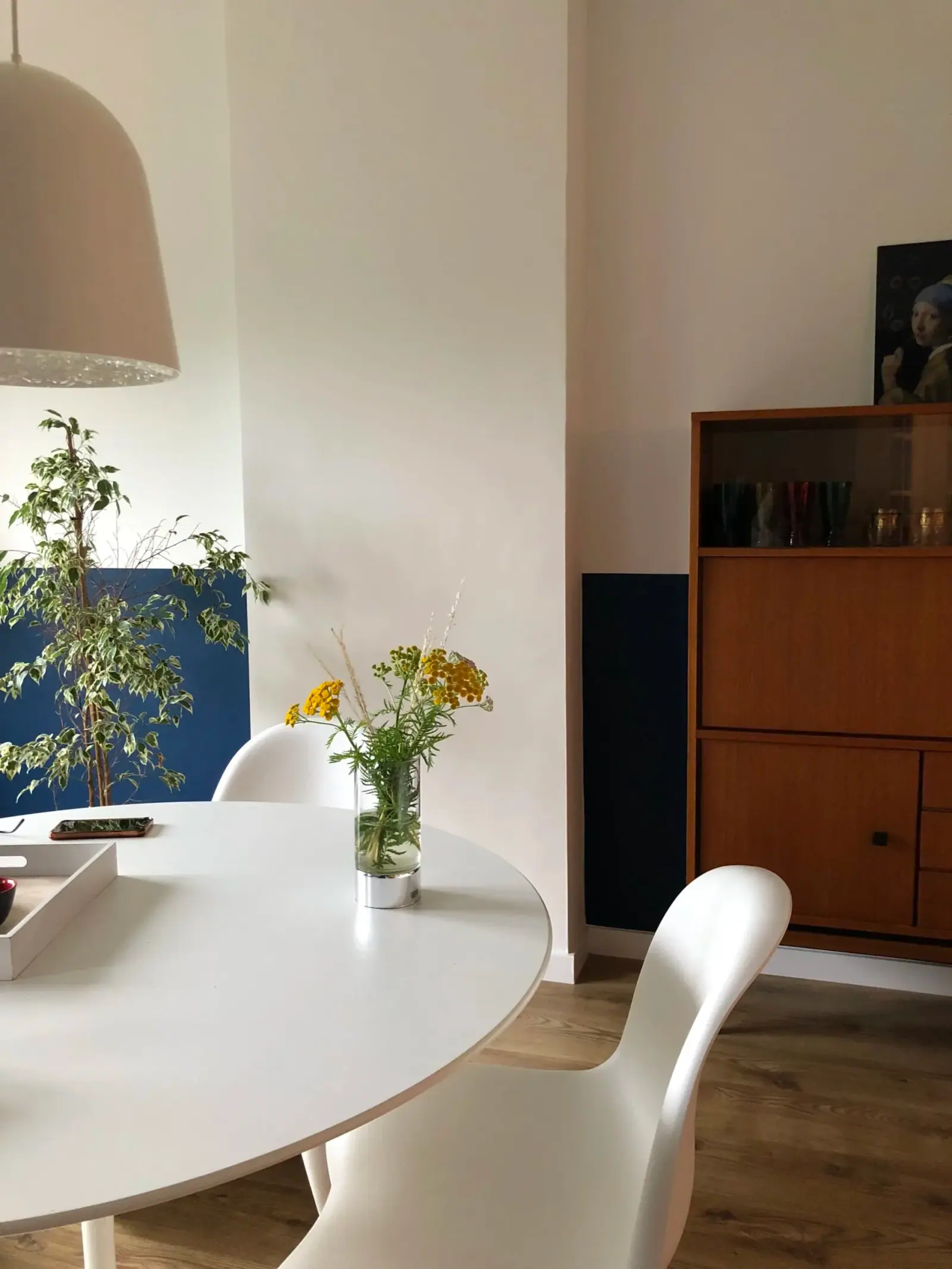 Rive Gauche — coin repas, table ronde blanche et enfilade vintage en teck